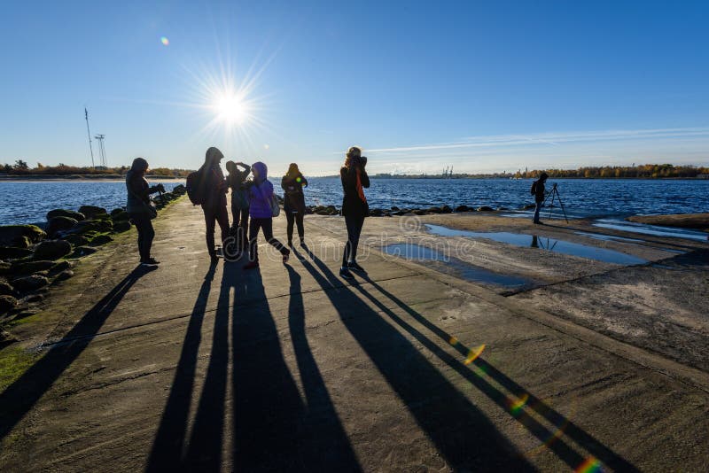 La gente che gode del tramonto sul frangiflutti nel mare con il lightho immagine stock libera da diritti