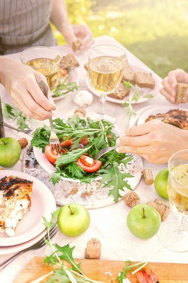 La gente come en el jardín en la tabla Concepto de la cena con el vino en el aire fresco Pescados y ensaladas asados a la parrill imágenes de archivo libres de regalías La gente come en el jardín en la tabla Concepto de la cena con el vino en el aire fresco Pescados y ensaladas asados a la parrill imágenes de archivo libres de regalías