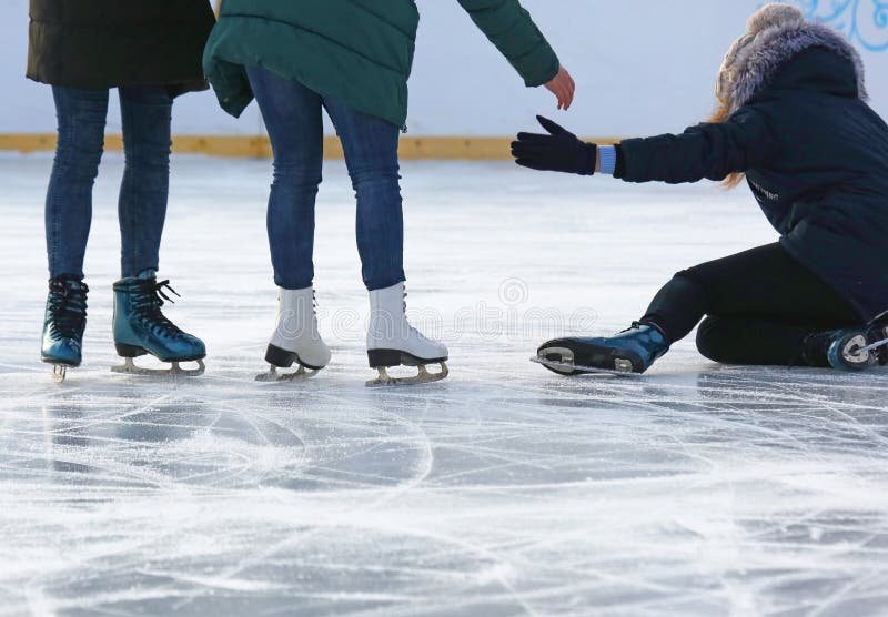 La gente contribuisce a alzarsi dopo una caduta che pattina sulla pista di pattinaggio sul ghiaccio