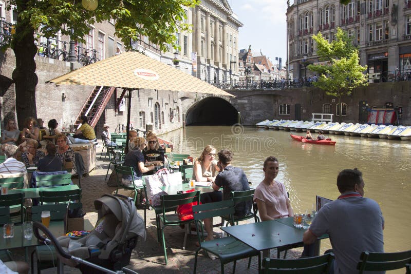 La gente se sienta y bebe en el café al aire libre en centro de ciudad de Utrecht medieval en Holanda fotografía de archivo libre de regalías La gente se sienta y bebe en el café al aire libre en centro de ciudad de Utrecht medieval en Holanda fotografía de archivo libre de regalías