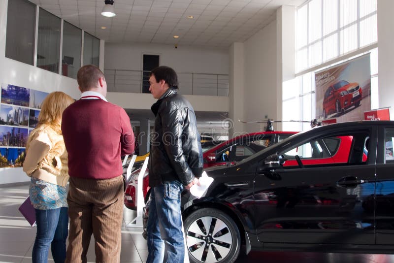 La gente sta vicino alle nuove automobili nella sala d'esposizione fotografia stock libera da diritti