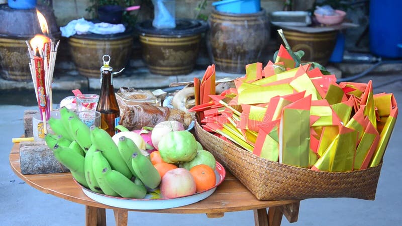 La gente tailandesa se prepara y poniendo la comida de ofrecimiento sacrificatoria en la tabla de madera para ruegue a dios