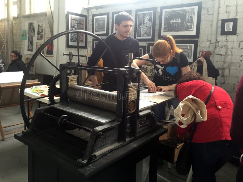La gente trabaja en la impresora vieja en taller del arte foto de archivo La gente trabaja en la impresora vieja en taller del arte foto de archivo