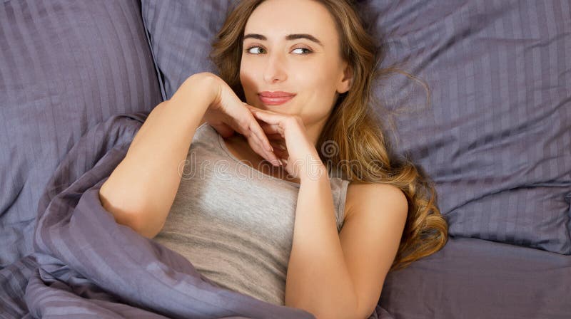 La giovane bella donna graziosa sul letto in appartamento moderno che sorride dopo sveglia fotografie stock libere da diritti La giovane bella donna graziosa sul letto in appartamento moderno che sorride dopo sveglia fotografie stock libere da diritti