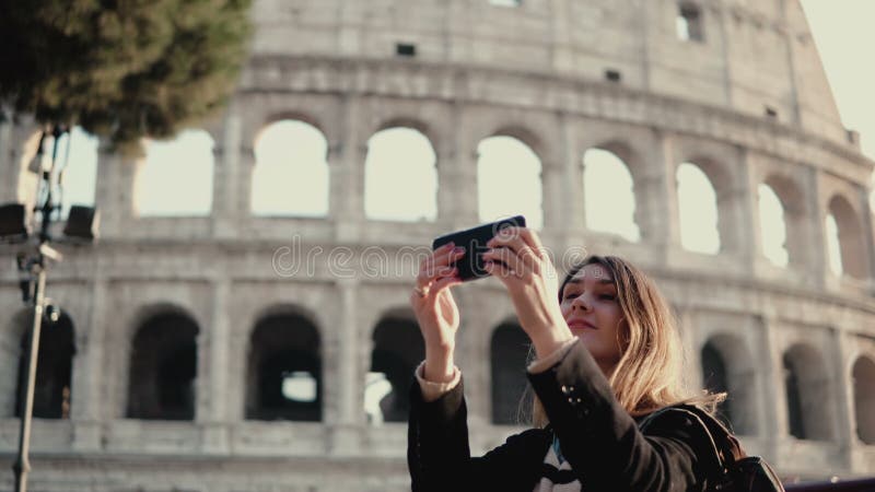 La giovane bella donna prende il selfie sullo smartphone Donna che cammina a Roma, Italia vicino al Colosseum immagine stock La giovane bella donna prende il selfie sullo smartphone Donna che cammina a Roma, Italia vicino al Colosseum immagine stock