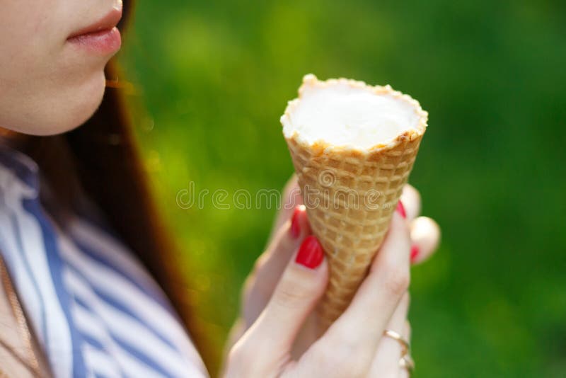 La giovane bella ragazza con capelli scorrenti lunghi mangia il gelato immagine stock La giovane bella ragazza con capelli scorrenti lunghi mangia il gelato immagine stock