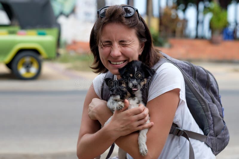 La giovane donna abbraccia due piccoli cuccioli Li trova nel riparo animale fotografie stock libere da diritti La giovane donna abbraccia due piccoli cuccioli Li trova nel riparo animale fotografie stock libere da diritti