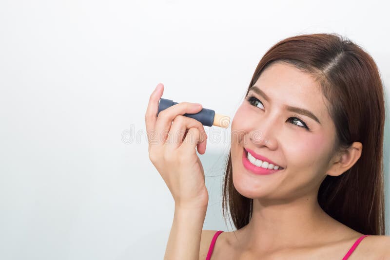 La giovane donna applica il correttore sotto l'occhio immagine stock La giovane donna applica il correttore sotto l'occhio immagine stock
