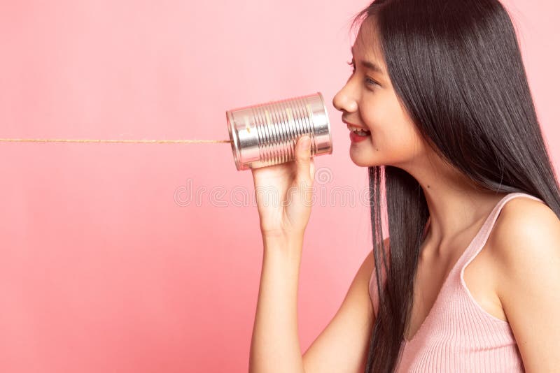 La giovane donna asiatica con latta barattolo telefonare fotografia stock La giovane donna asiatica con latta barattolo telefonare fotografia stock