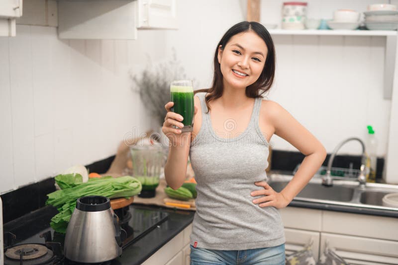 La giovane donna asiatica gode del frullato vegetariano sano per peso l