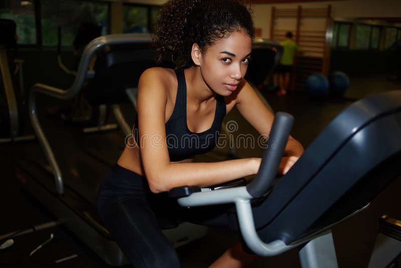La giovane donna attraente con una figura snella e una pelle scura è stata cardio allenamento nel centro di forma fisica immagine stock libera da diritti La giovane donna attraente con una figura snella e una pelle scura è stata cardio allenamento nel centro di forma fisica immagine stock libera da diritti