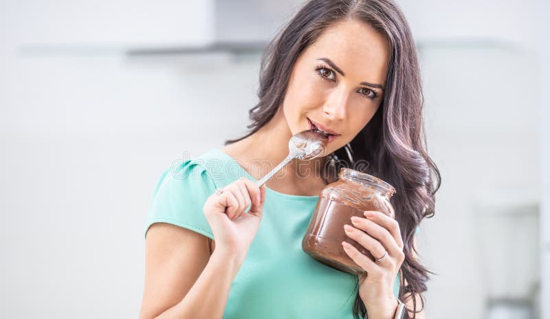 La giovane donna bellissima gode emotivamente del cioccolato o della crema nocciole fotografia stock libera da diritti