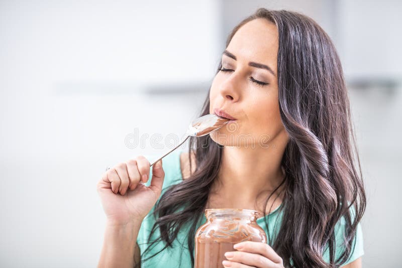 La giovane donna bellissima gode emotivamente del cioccolato o della crema nocciole fotografia stock libera da diritti