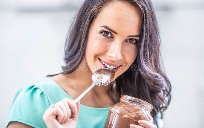 La giovane donna bellissima gode emotivamente del cioccolato o della crema nocciole fotografie stock