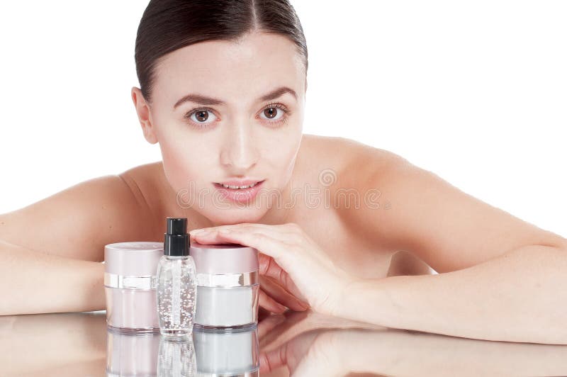 La giovane donna con una pelle ben curato vicino al screma i cosmetici. fotografia stock La giovane donna con una pelle ben curato vicino al screma i cosmetici. fotografia stock