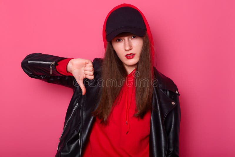 La giovane donna di modo utilizza il rossetto rosso luminoso, indossa la camicia, il bomber ed il berretto nero alla moda Il tena fotografia stock libera da diritti La giovane donna di modo utilizza il rossetto rosso luminoso, indossa la camicia, il bomber ed il berretto nero alla moda Il tena fotografia stock libera da diritti
