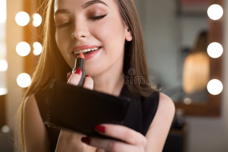 La giovane donna elegante sta godendo dei cosmetici professionali immagine stock La giovane donna elegante sta godendo dei cosmetici professionali immagine stock