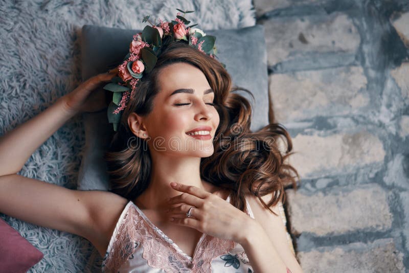 La giovane donna felice che si trova sul letto con gli occhi chiusi dopo sveglia fotografie stock La giovane donna felice che si trova sul letto con gli occhi chiusi dopo sveglia fotografie stock