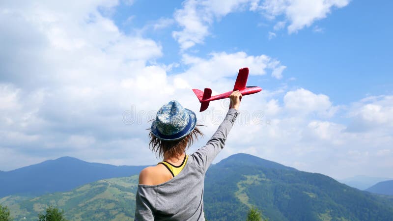 La giovane donna graziosa di nuovo alla macchina fotografica e tiene il modello rosso dell'aereo nel ruach Concetto del viaggio e