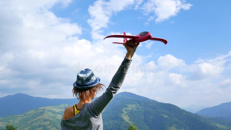 La giovane donna graziosa di nuovo alla macchina fotografica e tiene il modello rosso dell'aereo nel ruach Concetto del viaggio e