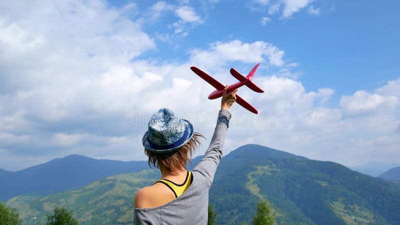 La giovane donna graziosa di nuovo alla macchina fotografica e tiene il modello rosso dell'aereo nel ruach Concetto del viaggio e