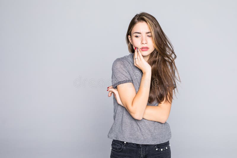 La giovane donna ha un mal di denti isolata su un fondo grigio immagine stock La giovane donna ha un mal di denti isolata su un fondo grigio immagine stock