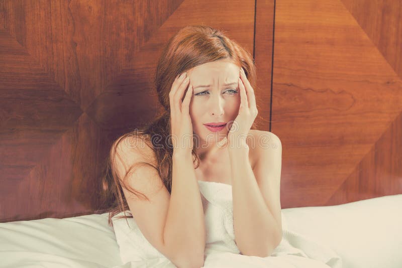 La giovane donna preoccupata che si situa a letto non può cadere addormentato ha emicrania fotografia stock libera da diritti La giovane donna preoccupata che si situa a letto non può cadere addormentato ha emicrania fotografia stock libera da diritti