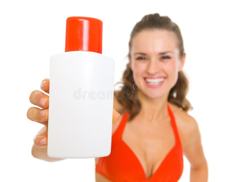 La donna sorridente in costume da bagno che mostra il sole blocca la crema fotografia stock libera da diritti La donna sorridente in costume da bagno che mostra il sole blocca la crema fotografia stock libera da diritti