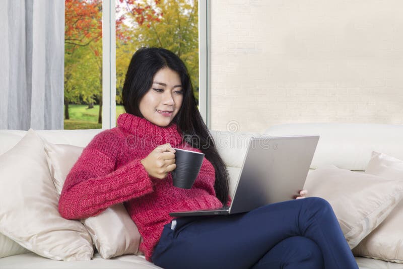 Giovane donna tiene tè e laptop fotografia stock libera da diritti