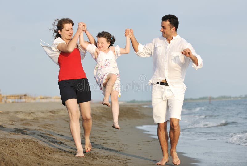 La giovane famiglia felice ha divertimento sulla spiaggia al tramonto fotografia stock libera da diritti La giovane famiglia felice ha divertimento sulla spiaggia al tramonto fotografia stock libera da diritti