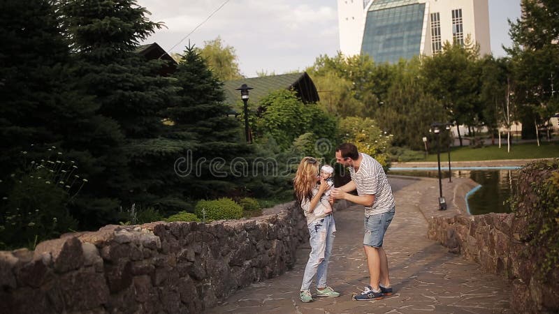 La giovane famiglia felice sta divertendosi nel parco all'aperto un giorno soleggiato