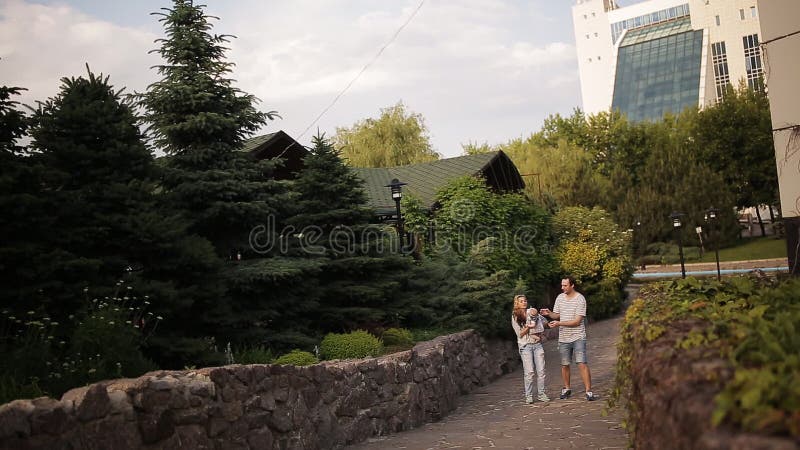 La giovane famiglia felice sta divertendosi nel parco all'aperto un giorno soleggiato