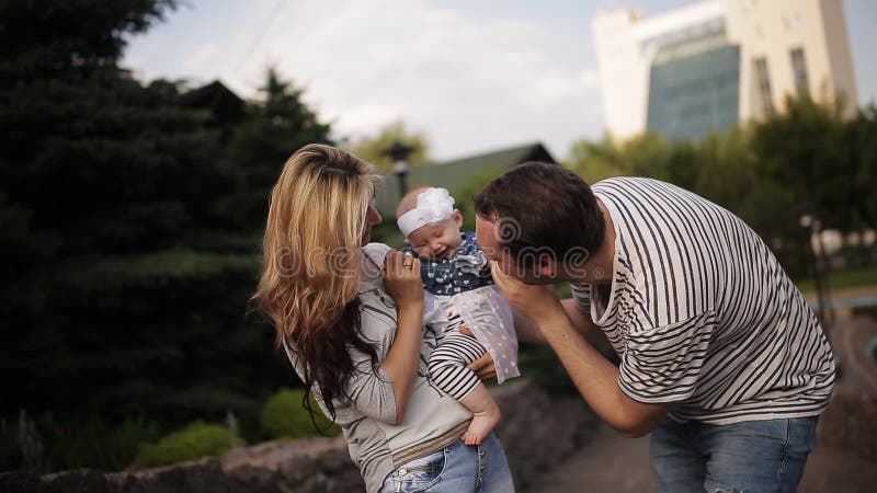 La giovane famiglia felice sta divertendosi nel parco all'aperto un giorno soleggiato