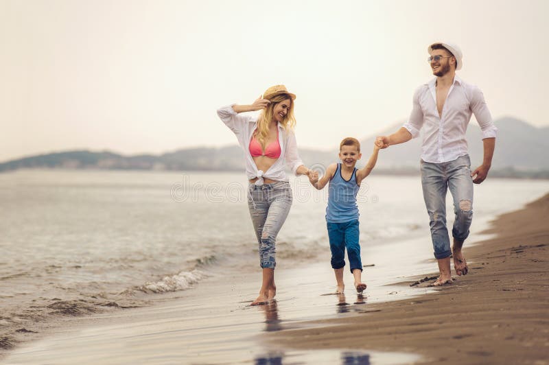 La giovane famiglia si diverte sulla spiaggia per funzionare e saltare fotografia stock libera da diritti La giovane famiglia si diverte sulla spiaggia per funzionare e saltare fotografia stock libera da diritti