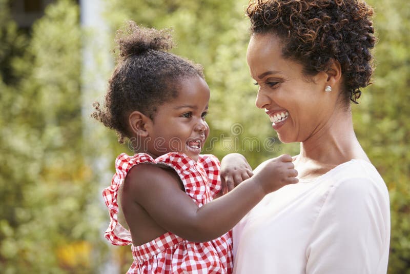 La giovane madre afroamericana tiene la figlia del bambino in giardino