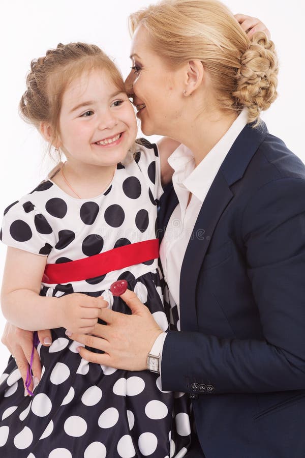 La giovane madre bisbiglia alla figlia in orecchio, primo piano fotografia stock La giovane madre bisbiglia alla figlia in orecchio, primo piano fotografia stock