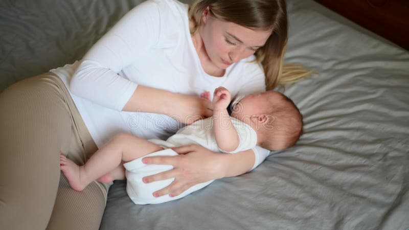 La giovane madre mette il letto di sonno per bambini gli dà un pacificatore che sussurra la testa che sussurra parole tenue. conce video d archivio