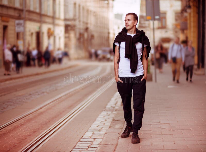 La giovane passeggiata dell'uomo del viaggiatore da solo da vecchio europen la via immagini stock libere da diritti La giovane passeggiata dell'uomo del viaggiatore da solo da vecchio europen la via immagini stock libere da diritti