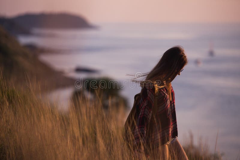 La giovane ragazza alla moda dei pantaloni a vita bassa gode del tramonto sul punto di vista Donna di viaggio con lo zaino fotografia stock La giovane ragazza alla moda dei pantaloni a vita bassa gode del tramonto sul punto di vista Donna di viaggio con lo zaino fotografia stock
