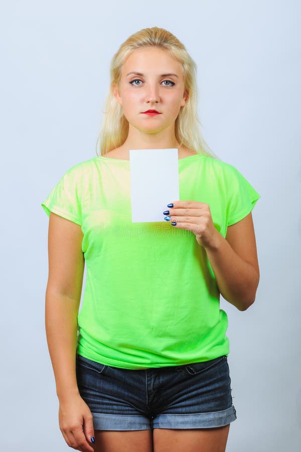 La giovane ragazza bionda tiene il biglietto da visita immagine stock libera da diritti La giovane ragazza bionda tiene il biglietto da visita immagine stock libera da diritti