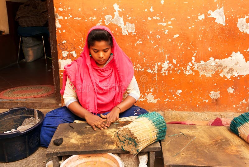 La giovane ragazza indiana che lavora con i sandali dell'aroma incense alla casa tradizionale con le pareti variopinte fotografia stock La giovane ragazza indiana che lavora con i sandali dell'aroma incense alla casa tradizionale con le pareti variopinte fotografia stock