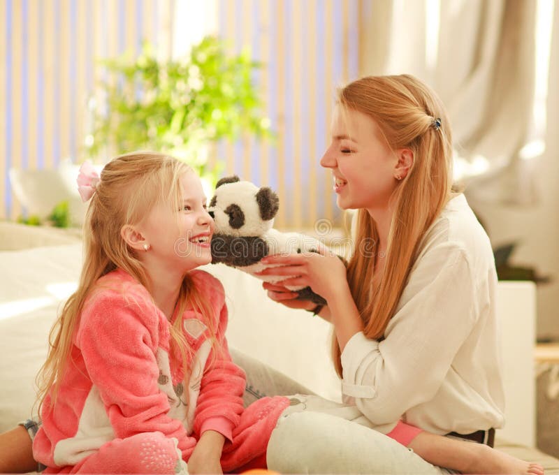 La giovani madre e figlia stanno divertendo il gioco a casa, il parenting e lo svago felici della famiglia immagine stock La giovani madre e figlia stanno divertendo il gioco a casa, il parenting e lo svago felici della famiglia immagine stock