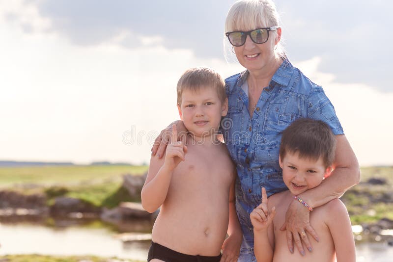 La grand-mère de sourire étreint deux petits-enfants images stock La grand-mère de sourire étreint deux petits-enfants images stock