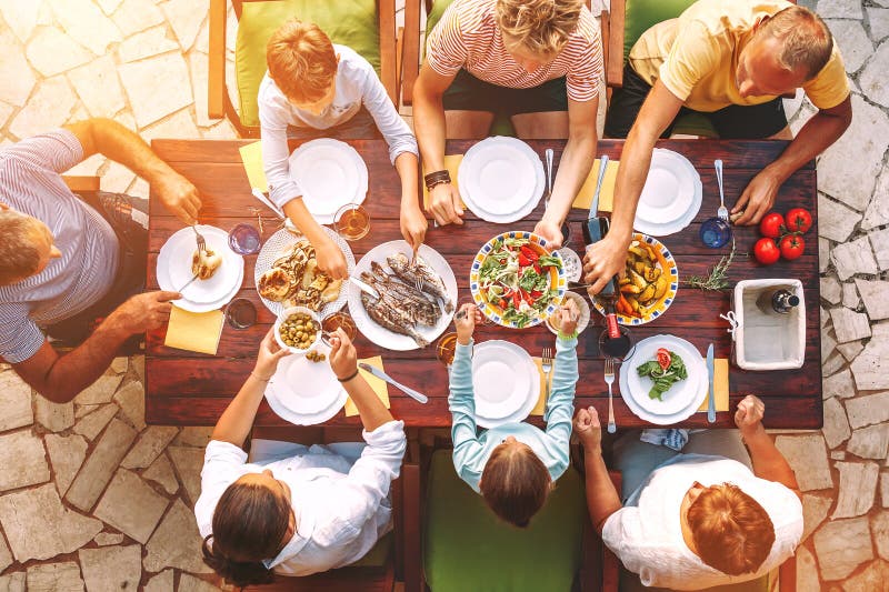 La grande famiglia ha una cena con il piatto cucinato fresco sul terrazzo aperto del giardino fotografia stock