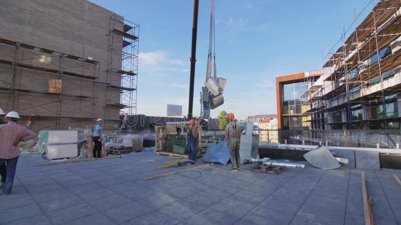 La grue transporte les détails de ventilation de l'air aux constructeurs sur le toit