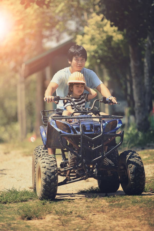La guida della figlia e del padre sul atv del quadrato sulla sporcizia sistema immagini stock libere da diritti La guida della figlia e del padre sul atv del quadrato sulla sporcizia sistema immagini stock libere da diritti