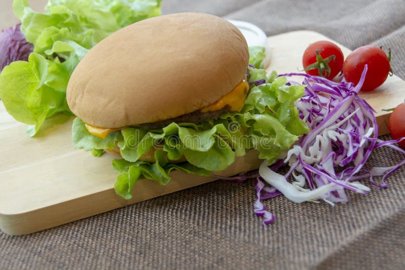 La hamburguesa se prepara con cerdo asado a la parrilla, queso, los tomates, la lechuga y la col p?rpura en la tabla imágenes de archivo libres de regalías La hamburguesa se prepara con cerdo asado a la parrilla, queso, los tomates, la lechuga y la col p?rpura en la tabla imágenes de archivo libres de regalías