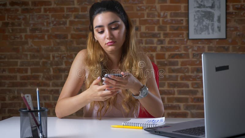 La hembra caucásica agradable está mecanografiando en el teclado, usando el ordenador portátil y paró repentinamente para contest