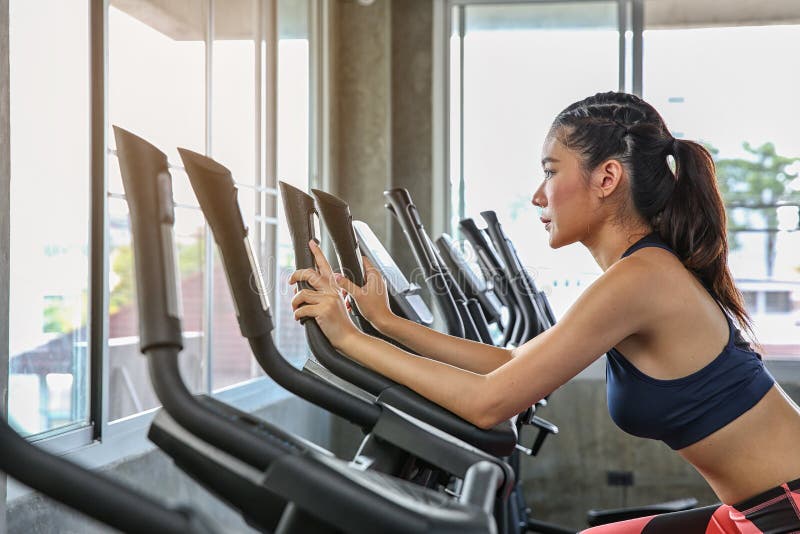 La hembra está completando un ciclo en el gimnasio Retrato de la muchacha que ejercita en las máquinas cardiias en el club de dep imágenes de archivo libres de regalías La hembra está completando un ciclo en el gimnasio Retrato de la muchacha que ejercita en las máquinas cardiias en el club de dep imágenes de archivo libres de regalías