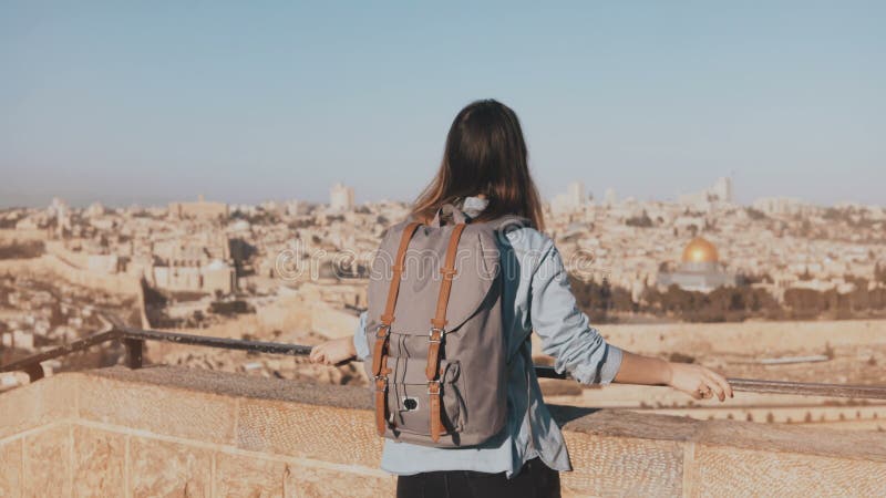 La hembra turística europea feliz aumenta las manos Israel, Jerusalén La muchacha con la mochila camina para ver viejo panorama d